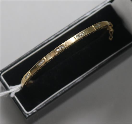 A 9ct gold and diamond hinged bangle, with pierced decoration, in fitted case.